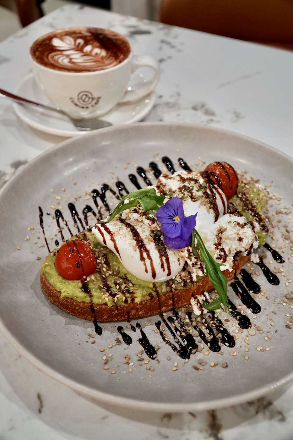 Avocado toast beside a branded Lumina Café coffee cup